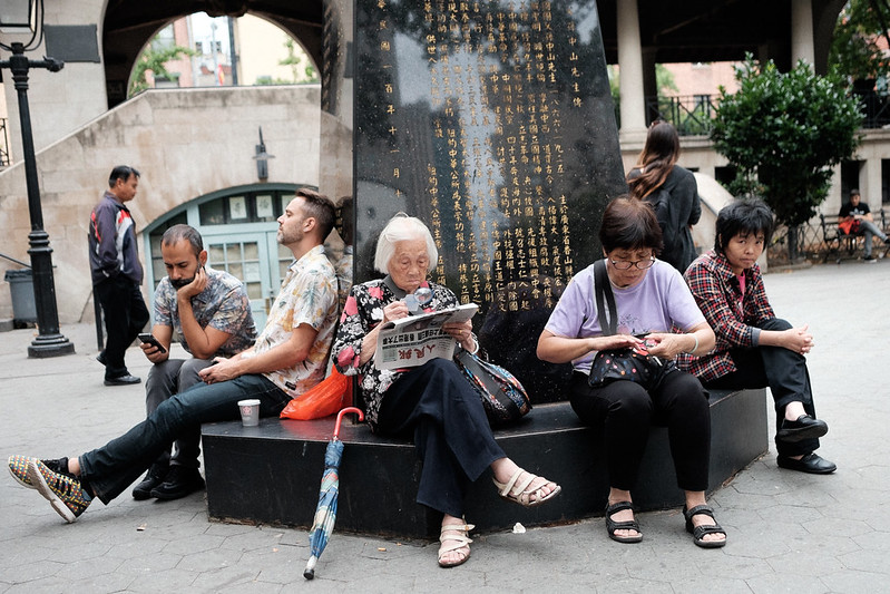 Group of people sit in a park in New York's Chinatown