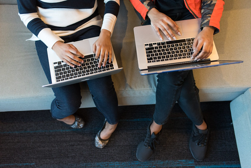 Two women use their laptops