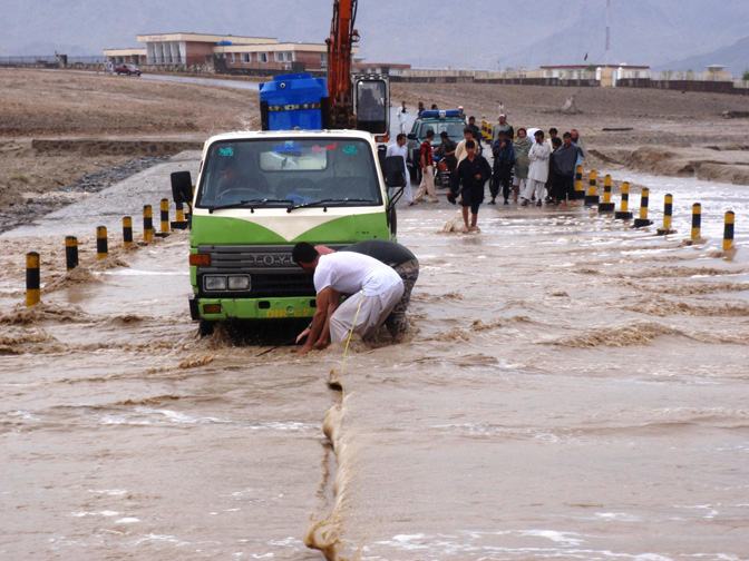 People pulling vehicles from a flooded road in an Afghan village