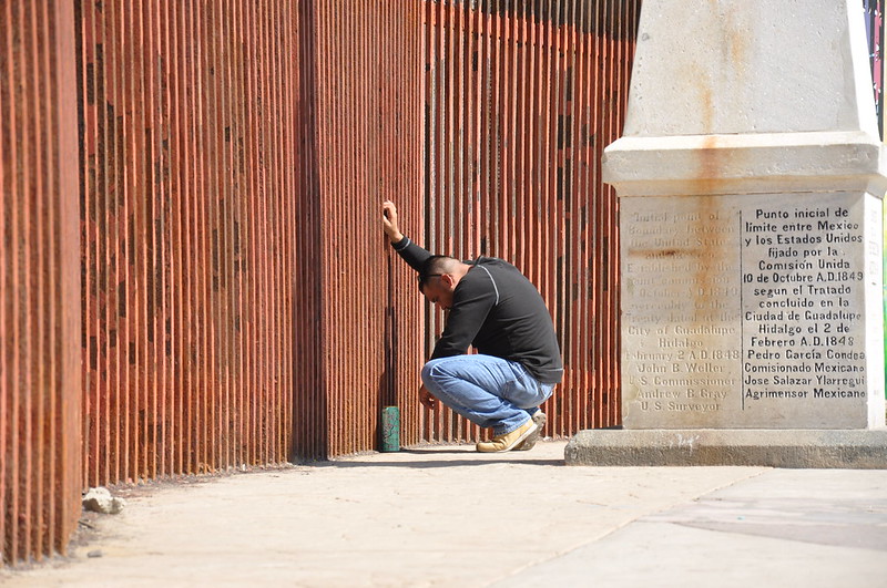 A man says goodbye to his partner through the border fence