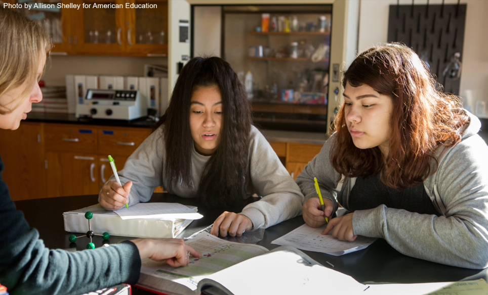 Two high school students with chemistry teacher