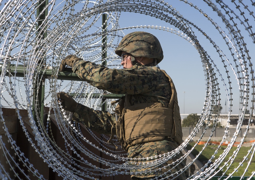U.S. Marine secures barbed-wire fencing at the California-Mexico border.