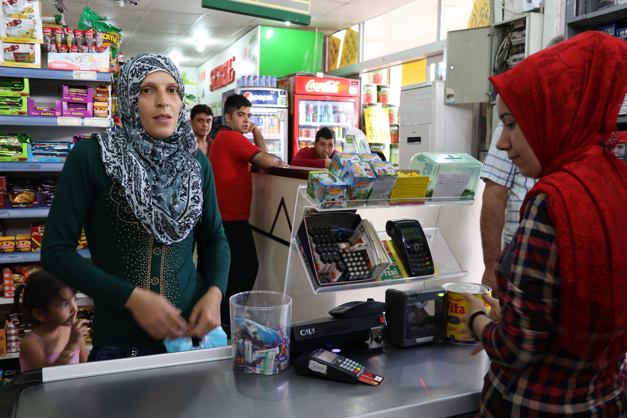 A Syrian refugee woman uses a special e-card to purchase food at a grocery store in Turkey.