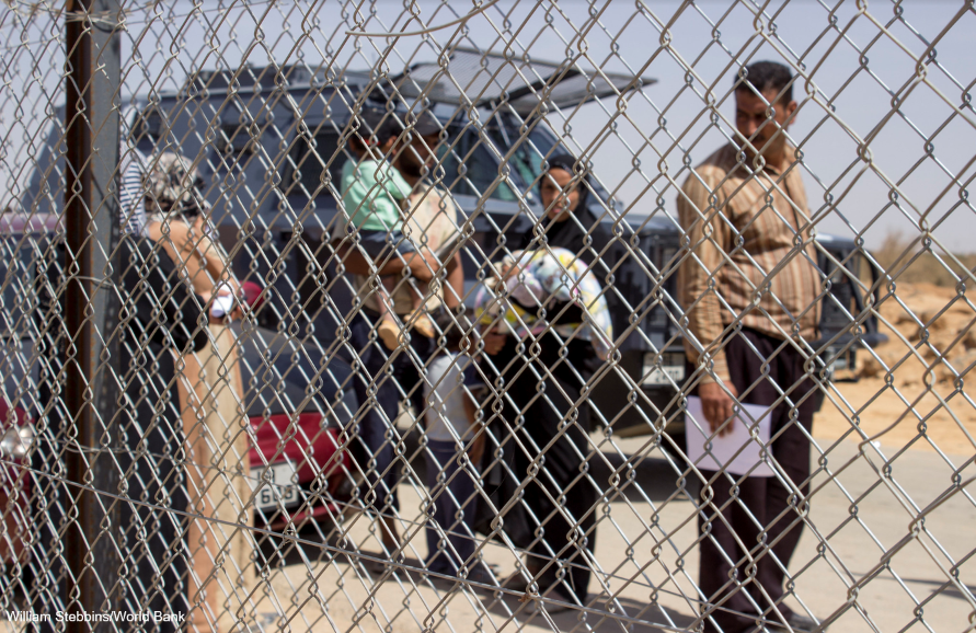 Syrian refugees standing by fence