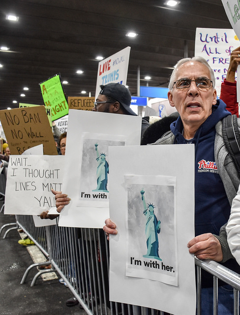 A man holds a sign protesting the travel ban at an airport