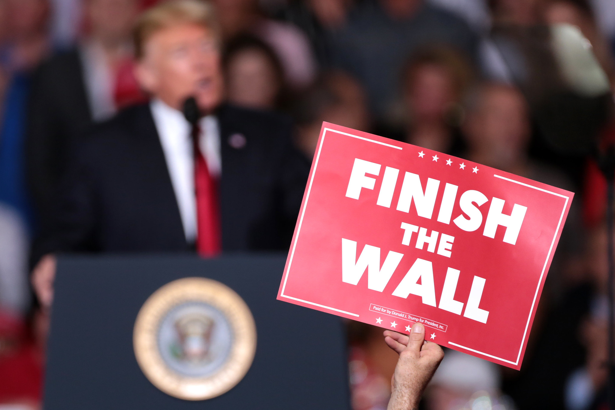 A supporter holds a sign reading "Finish the Wall" during a rally for President Donald Trump in Mesa, Arizona.