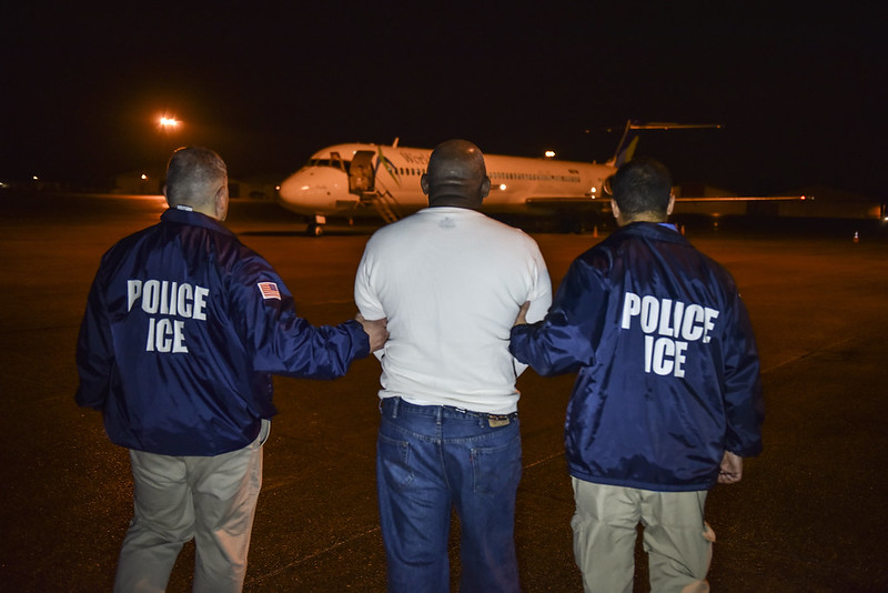 A migrant scheduled to be deported from the United States is escorted to a charter flight. 