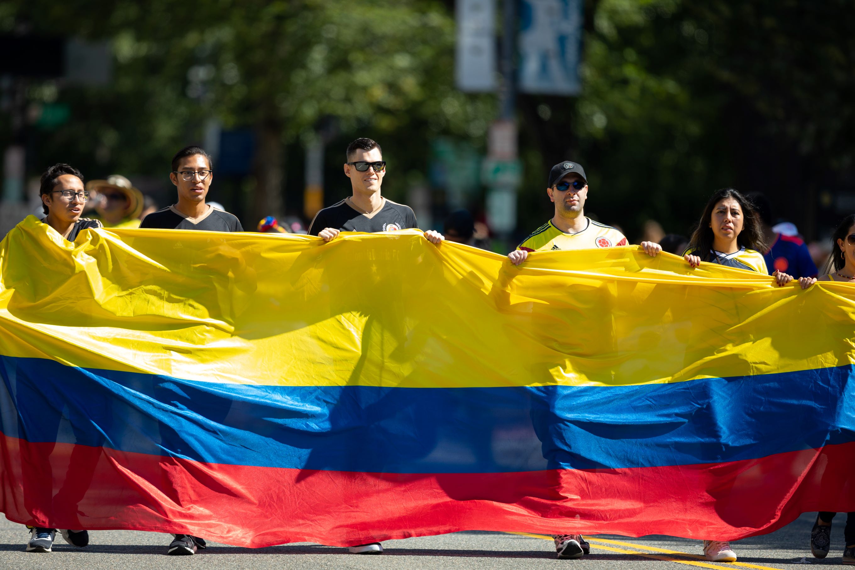 Varias personas portan una bandera gigante de Colombia en un desfile en Washington, DC.