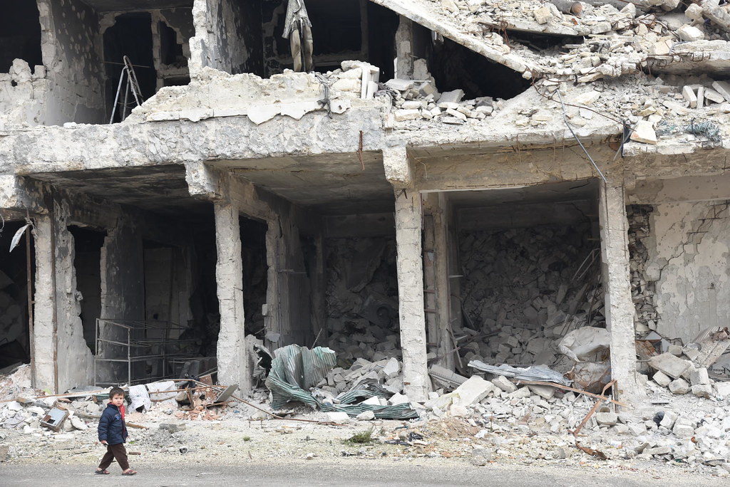 A child walks by a destroyed building in Syria.
